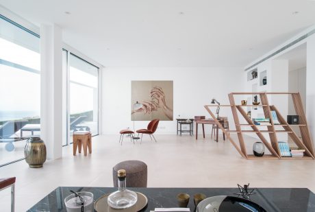 Spacious, modern living space with floor-to-ceiling windows, minimalist furniture, and eclectic decor.