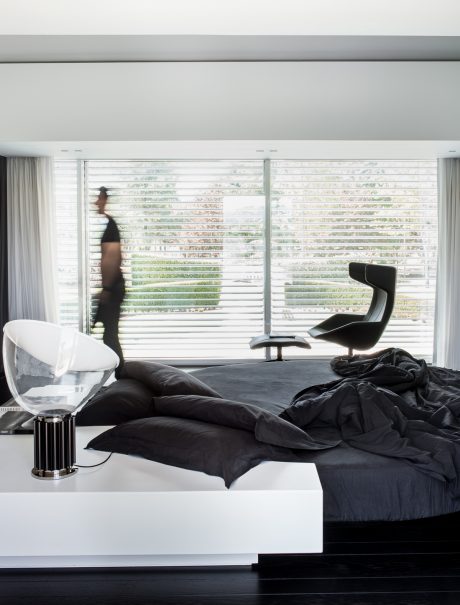 Sleek, modern bedroom with floor-to-ceiling windows, leather chaise, and minimalist decor.