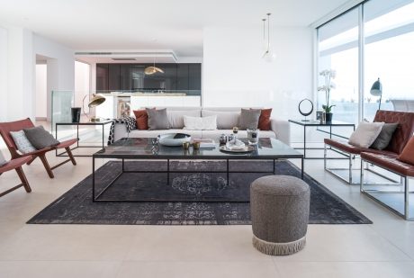 A modern living room with sleek furniture, dark accents, and large windows providing abundant natural light.