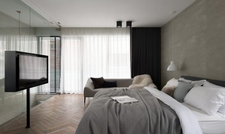 Sleek, modern bedroom with minimalist furnishings, wooden flooring, and textured walls.