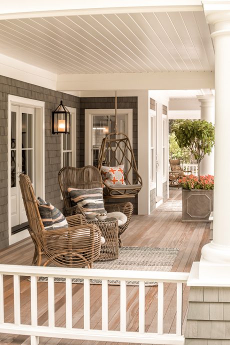 Cozy covered porch with wicker furniture, potted plants, and a warm, inviting atmosphere.