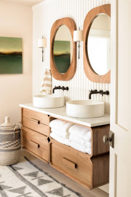 Rustic vanity with circular wood-framed mirrors, vessel sinks, and patterned rug.
