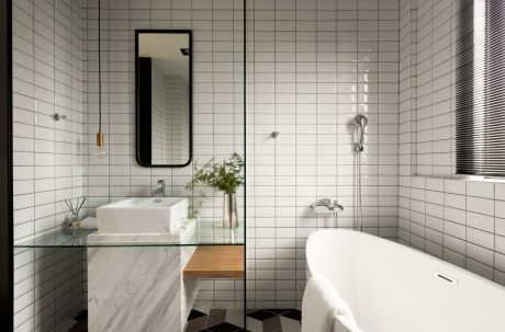 A modern bathroom with minimalist white tiles, a freestanding bathtub, and a floating vanity.