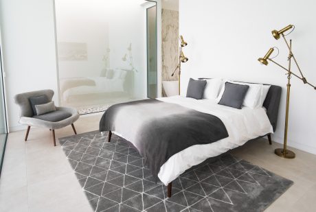 Spacious bedroom with minimalist design, gray accents, and sophisticated lighting.