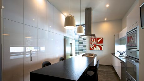 Sleek, minimalist kitchen design with grey cabinetry, pendant lights, and modern artwork.
