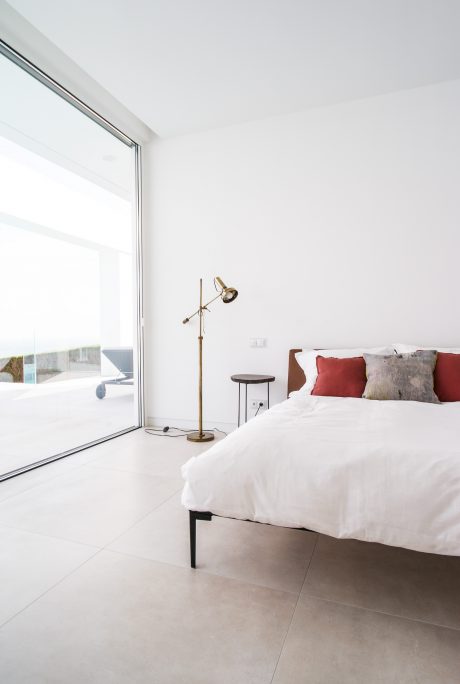 Modern bedroom with large windows offering scenic view, minimalist furnishings, and warm accents.