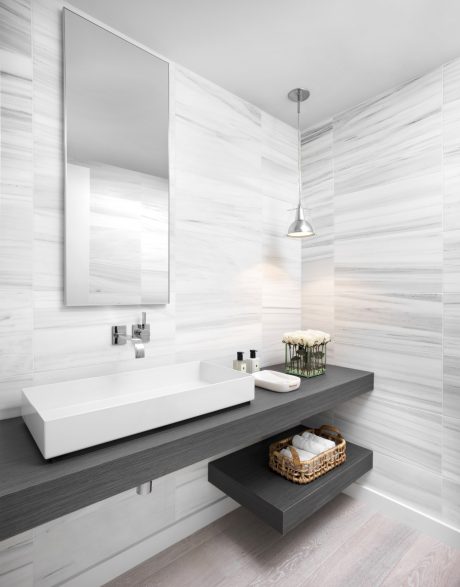 A minimalist bathroom with a floating vanity, large mirror, and pendant lighting.