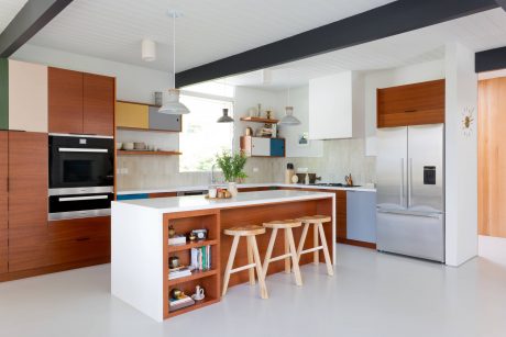 A modern, open-concept kitchen with colorful cabinetry, wooden accents, and a spacious island.
