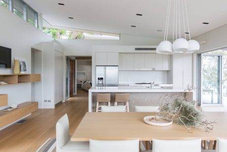 Sleek, modern kitchen and dining area with minimalist furnishings and floor-to-ceiling windows.
