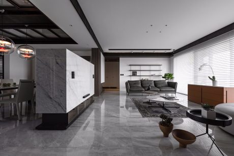 Spacious modern interior with sleek marble walls, suspended lighting, and minimalist furnishings.