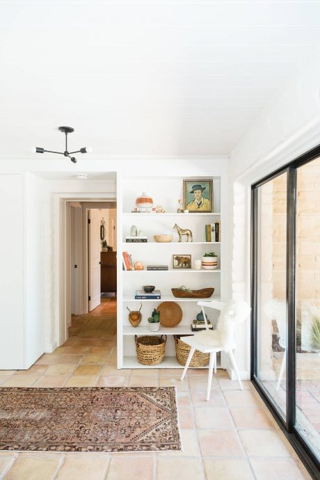 A cozy and stylish open-concept interior with rustic shelving, natural decor, and large windows.