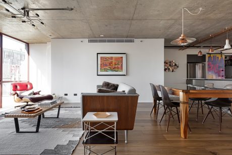 Open-concept living area with concrete ceiling, wood furniture, and eclectic lighting fixtures.