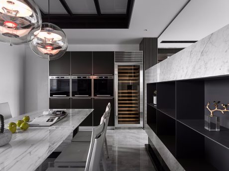 Sleek, modern kitchen with marble countertops, black cabinetry, and unique pendant lighting.