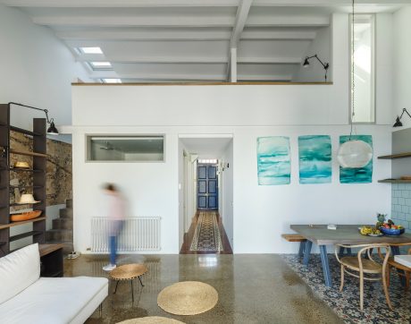 Bright, open-concept living space with exposed beams, wall art, and a concrete floor.