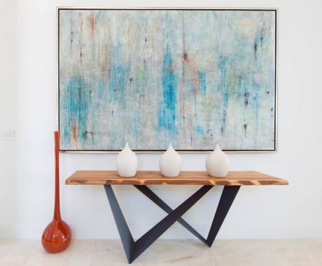 Modern abstract art piece on the wall, complemented by a wooden table and minimalist vases.
