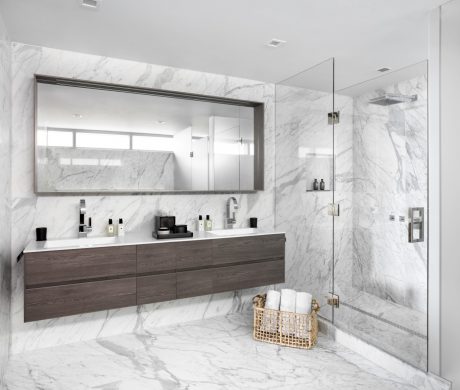 Spacious modern bathroom with marble walls, wood vanity, and integrated lighting.
