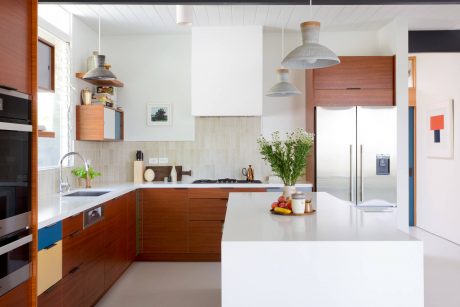 Modern kitchen with wooden cabinets, white countertops, and pendant lighting fixtures.