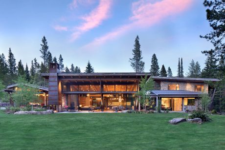 Expansive modern mountain lodge with stone exteriors, wood beams, and dramatic windows.