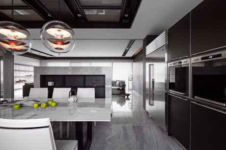 Sleek, modern kitchen with marble countertops, black cabinets, and contemporary light fixtures.