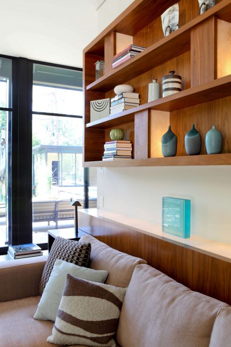 Warm, modern living room with wood shelving, decorative ceramics, and soft lighting.