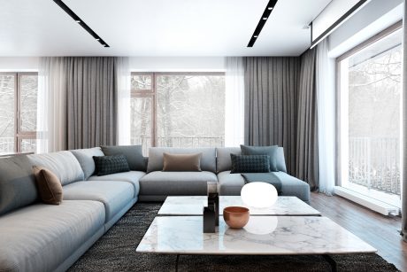Luxurious, contemporary living space with plush gray sectional, marble coffee table, and floor-to-ceiling windows.