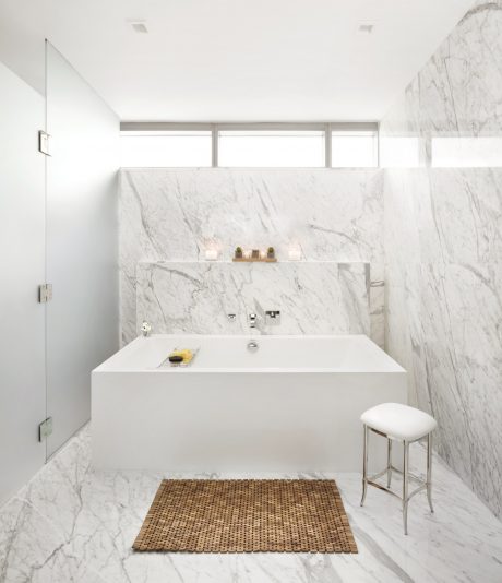 Minimalist bathroom with striking marble walls, freestanding tub, and wooden accents.