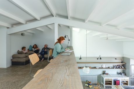 A cozy, open-concept loft with a wooden counter, shelves, and a seating area.