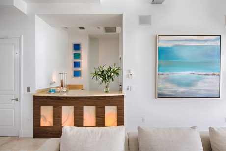 Spacious, light-filled room with a wooden bar, abstract artwork, and modern furniture.