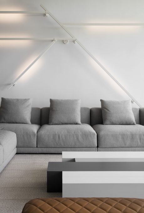 Minimalist living room with gray upholstered sofa, geometric coffee table, and sleek lighting.