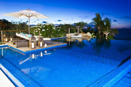 Elegant outdoor pool surrounded by tropical foliage and cozy seating areas.