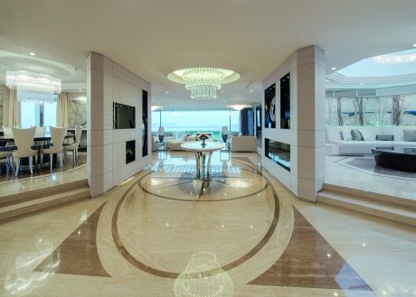 Spacious open-concept living area with sleek modern furnishings and grand chandelier.