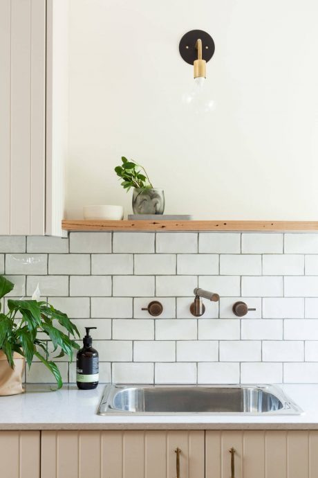 Modern kitchen with subway tile backsplash, wooden shelving, and brass fixtures.