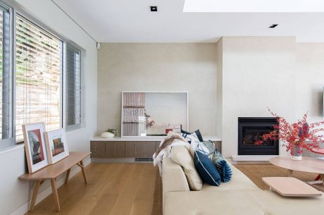 Minimalist living room with large window, fireplace, and wooden furniture.