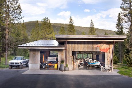 A rustic wooden cabin with a metal roof, housing various vehicles and outdoor equipment.