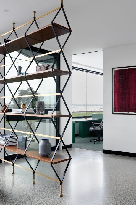 Striking geometric shelving unit with wooden shelves and brass accents, overlooking modern office.
