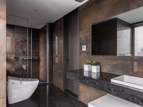 Sleek, modern bathroom featuring dark granite countertops, glass-enclosed shower, and minimalist decor.