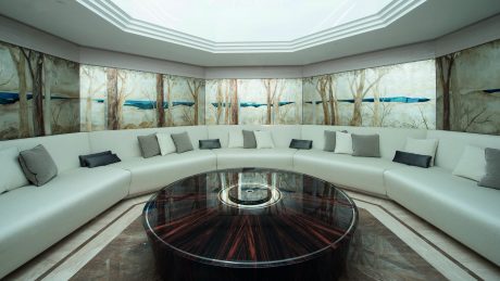 Luxurious curved seating arrangement around a glass-topped table in an ornate room.