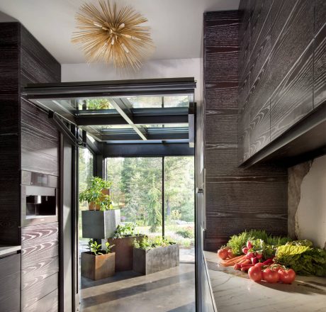 Sleek, modern kitchen with minimalist cabinets, pendant light, and floor-to-ceiling windows offering scenic views.