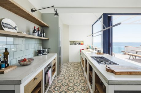 Well-designed kitchen with open shelving, patterned tile floor, and large windows offering scenic ocean views.