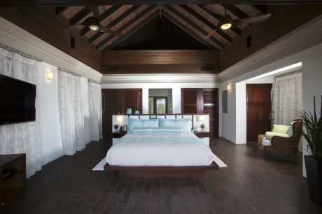 Spacious and elegant bedroom with vaulted wooden ceiling, large bed, and open layout.