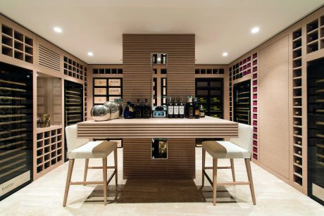 A sophisticated wine cellar with a modern, sleek design featuring wood paneling, built-in shelving, and a central tasting counter.