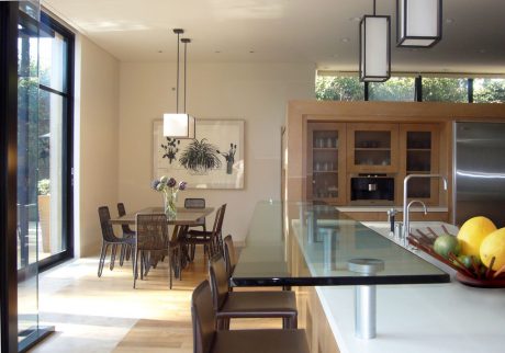 A modern kitchen and dining space with minimalistic furnishings and large windows.