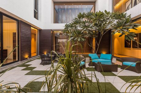 Luxurious indoor courtyard with lush tropical plants, modern furniture, and warm lighting.