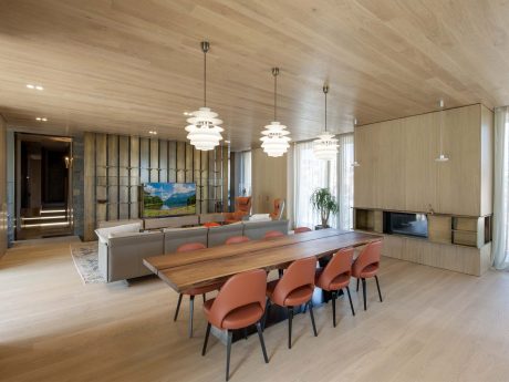 Spacious living room with wooden walls, modern lighting fixtures, and a large dining table.