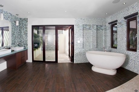 Sleek, modern bathroom with tiled walls, freestanding tub, and wooden flooring.