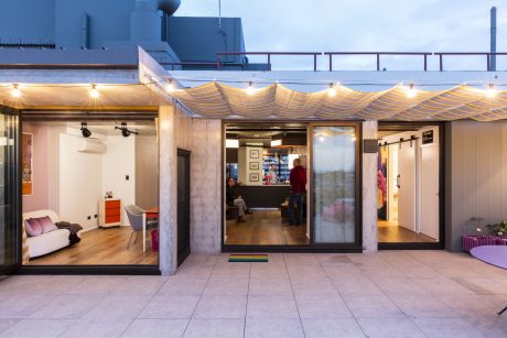 Modern industrial-style workspace with warm lighting, balcony, and modular furniture.