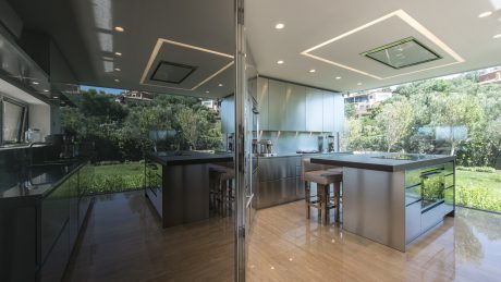 Sleek, modern kitchen with stainless steel appliances, floor-to-ceiling windows, and garden views.