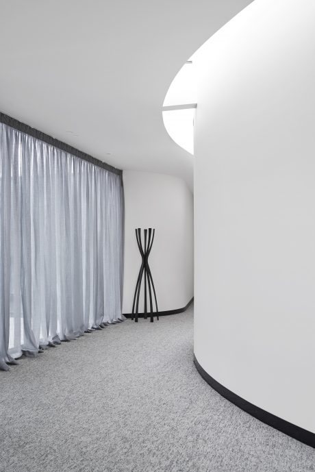 Sleek, minimalist design with curved white wall, dramatic curtains, and geometric sculpture.