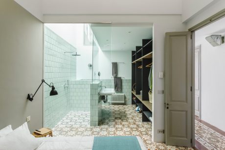A modern bathroom with a tiled shower, patterned floor, and built-in cabinetry.
