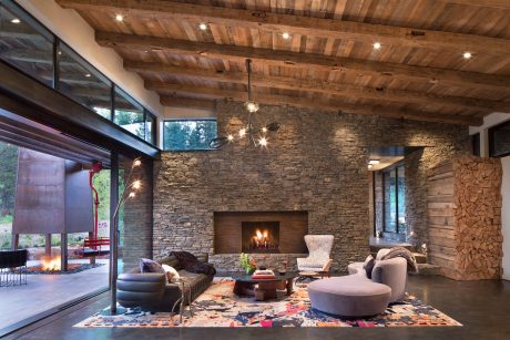 Rustic stone fireplace, wooden beams, and colorful rug in a cozy living room.